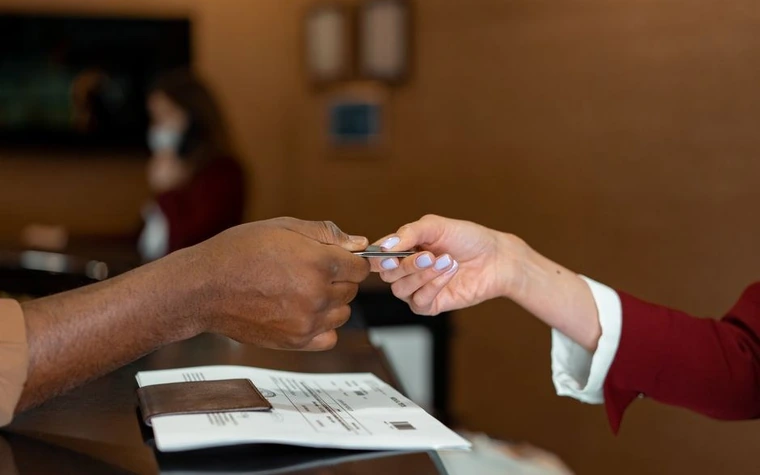 Hotel front desk clerk receiving a credit card from a guest at check-in