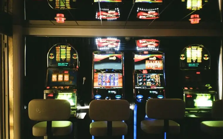 Rows of illuminated slot machines with colorful video screens in a dim casino