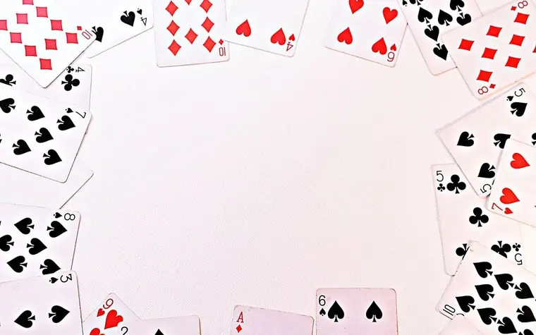 Standard playing cards spread in a circle on a white surface showing hearts, spades, diamonds and clubs