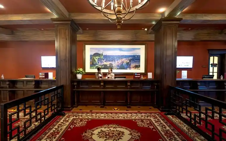 Hotel reception desk with wood columns, ornate chandelier and red patterned carpet